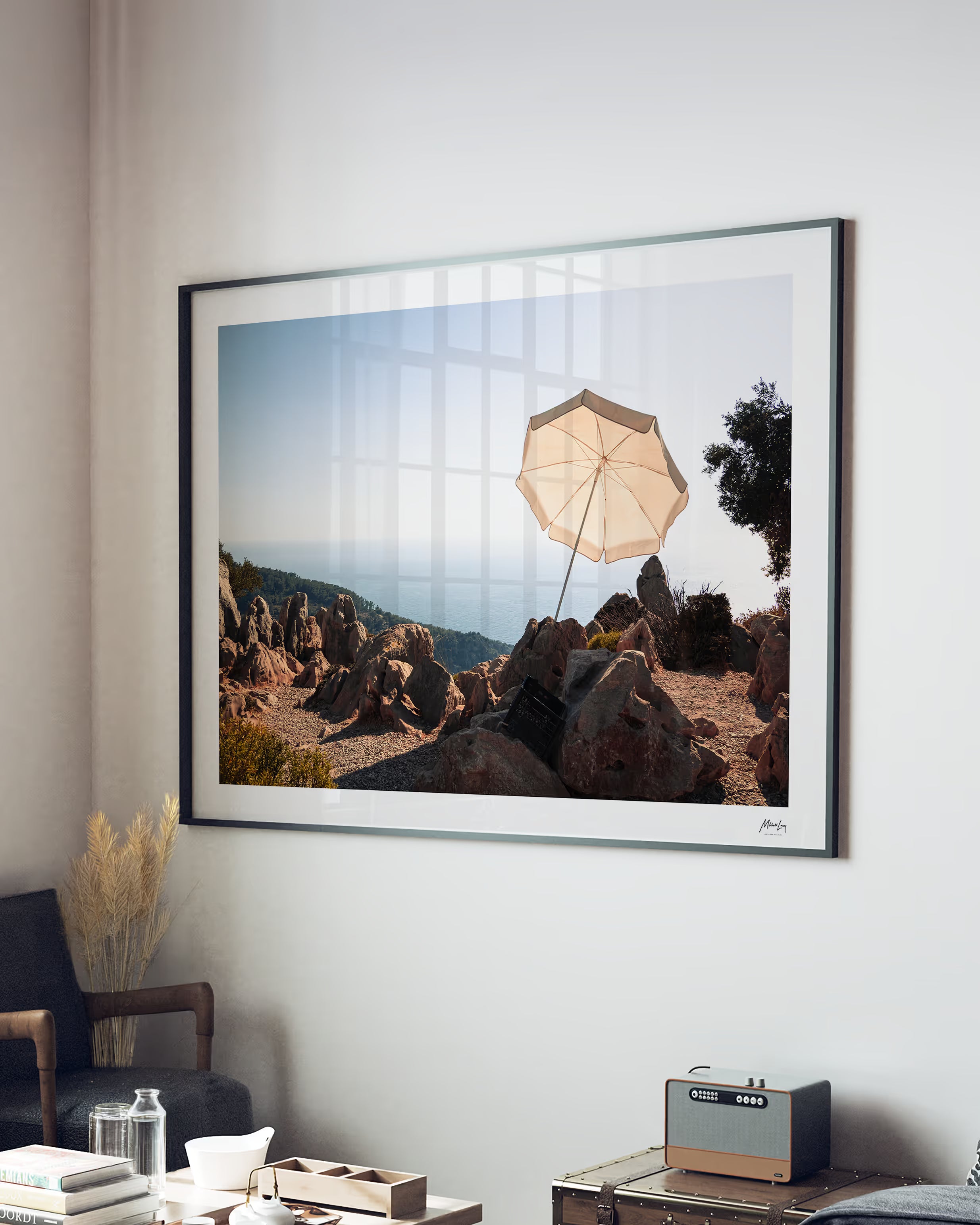 Framed artwork of a landscape with an umbrella on a rocky hillside, displayed in a living room.