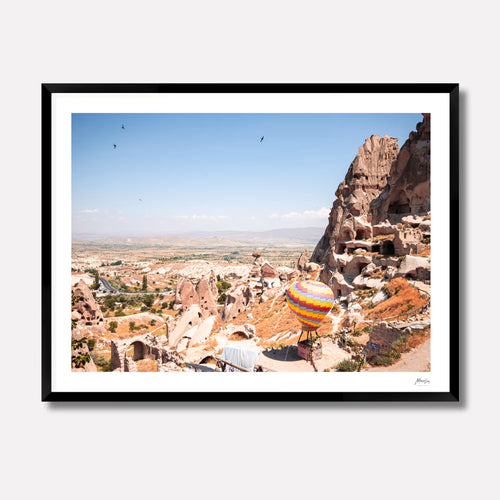 Framed photograph of a colorful hot air balloon over a rocky landscape with cave dwellings.