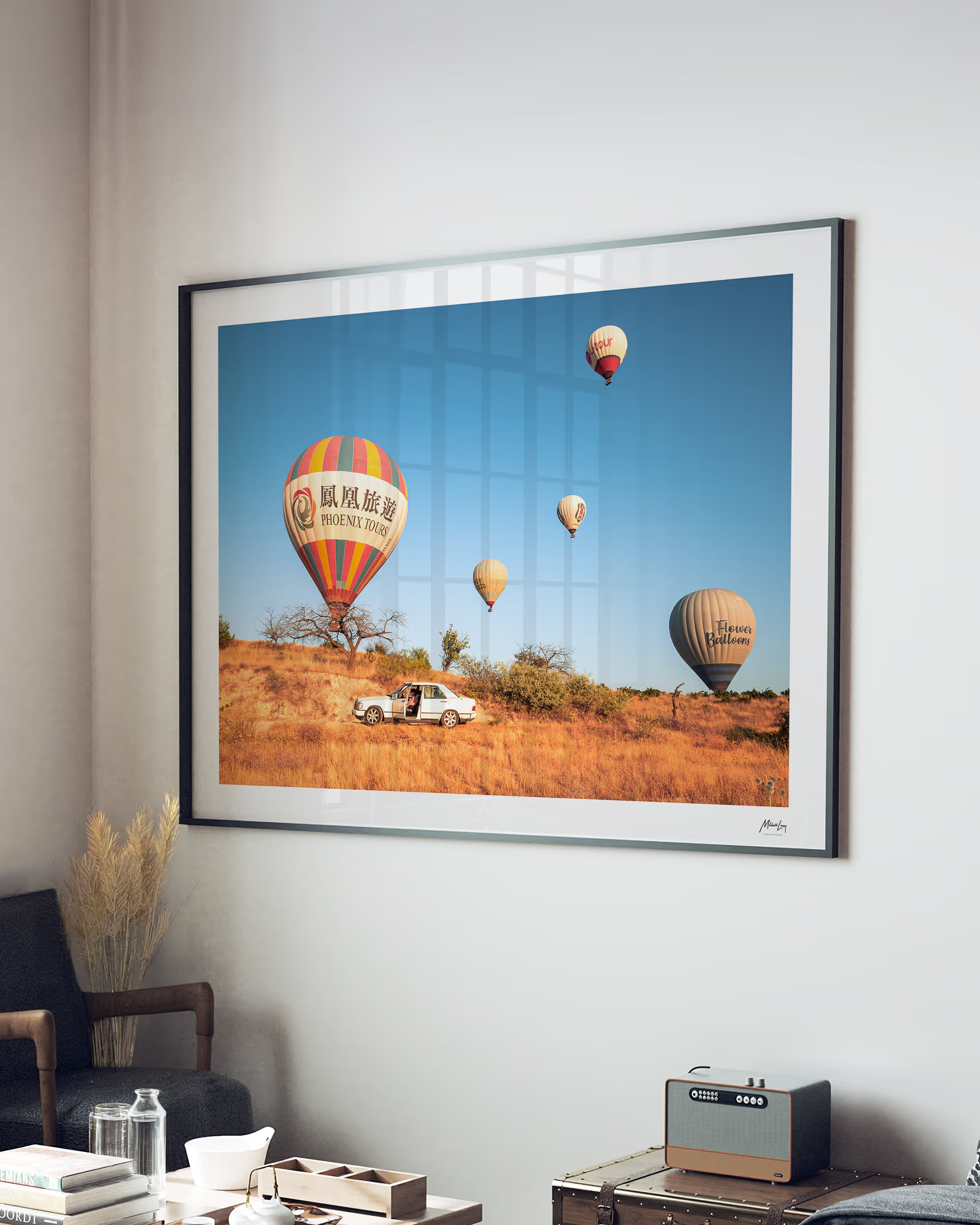 Framed artwork of hot air balloons over a field in a living room setting.