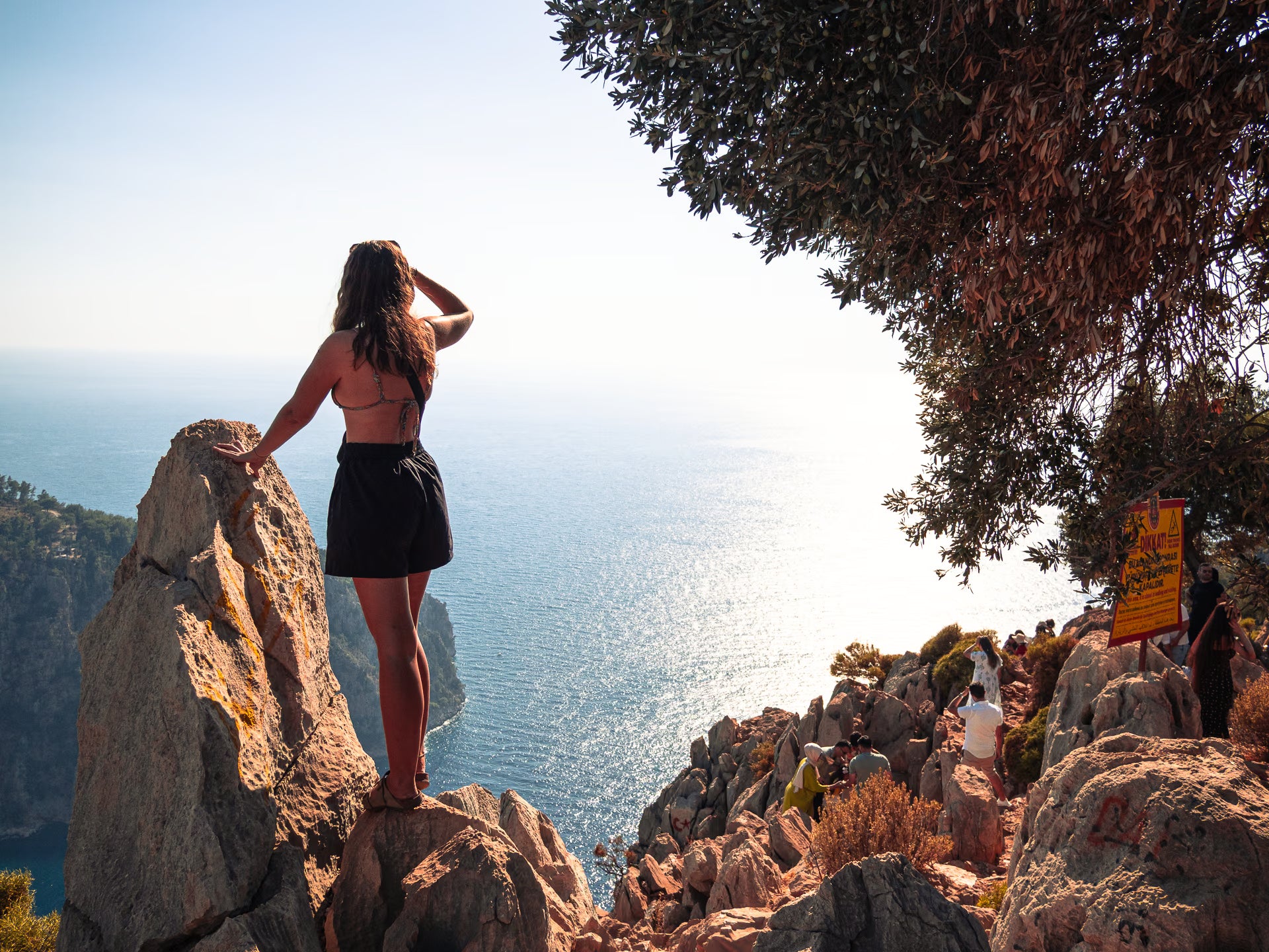 A woman standing on a coastal ridge overlooking the Mediterranean near Fethiye, Türkiye.